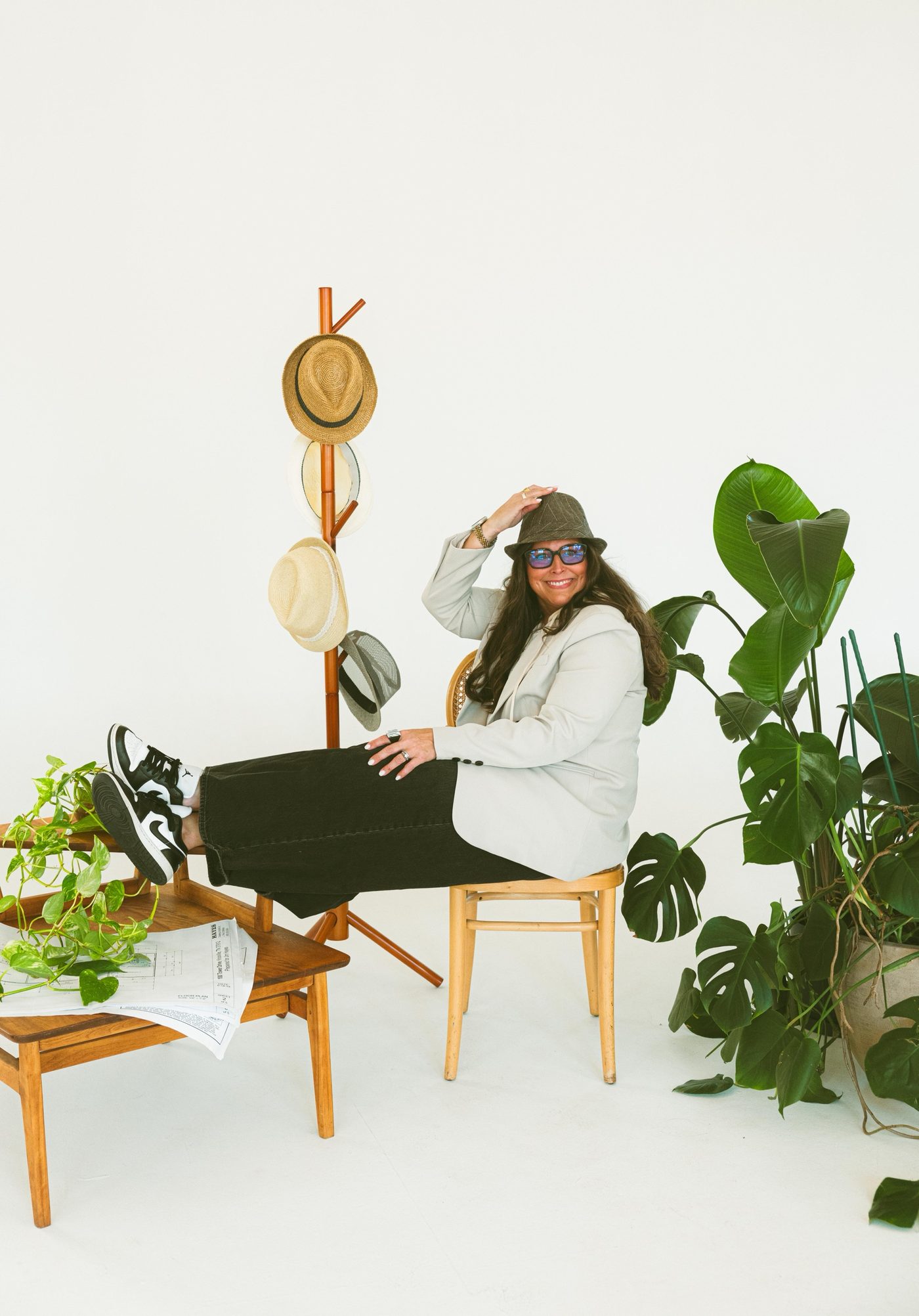 Tara Hayes relaxing beside her hat rack — the Broker in a Hat